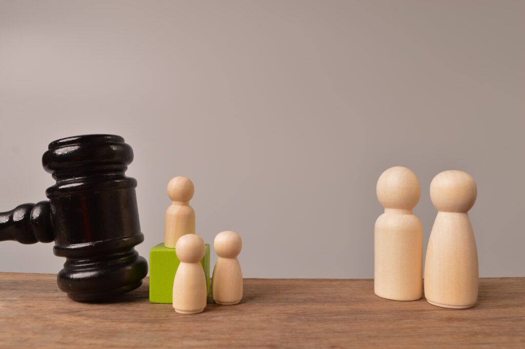 Judge’s gavel beside small wooden figures and larger figures, symbolizing the difference between hybrid and indictable offences in Canada.
