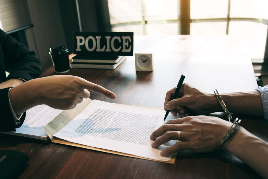 Police officer pointing to a document while a detained individual signs paperwork during an investigative detention.
