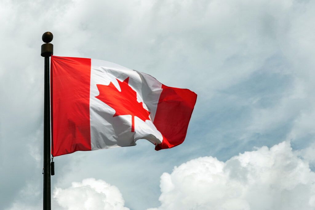Canadian flag flying on a flagpole, representing Charter rights and Section 11 protections for accused persons in Canada.