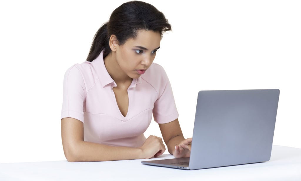 a woman sitting at a table looking at a laptop computer
