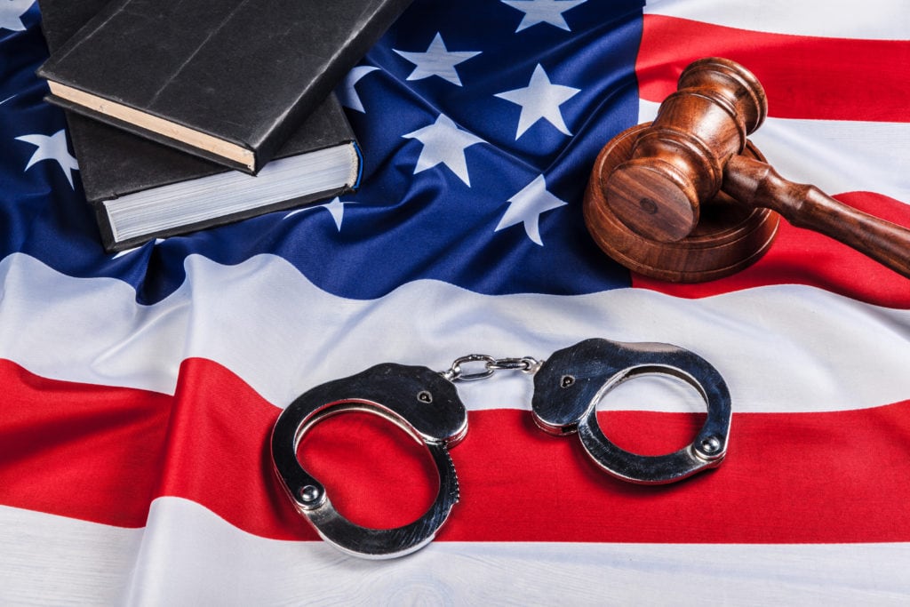 Gavel, handcuffs and american flag on wooden background.