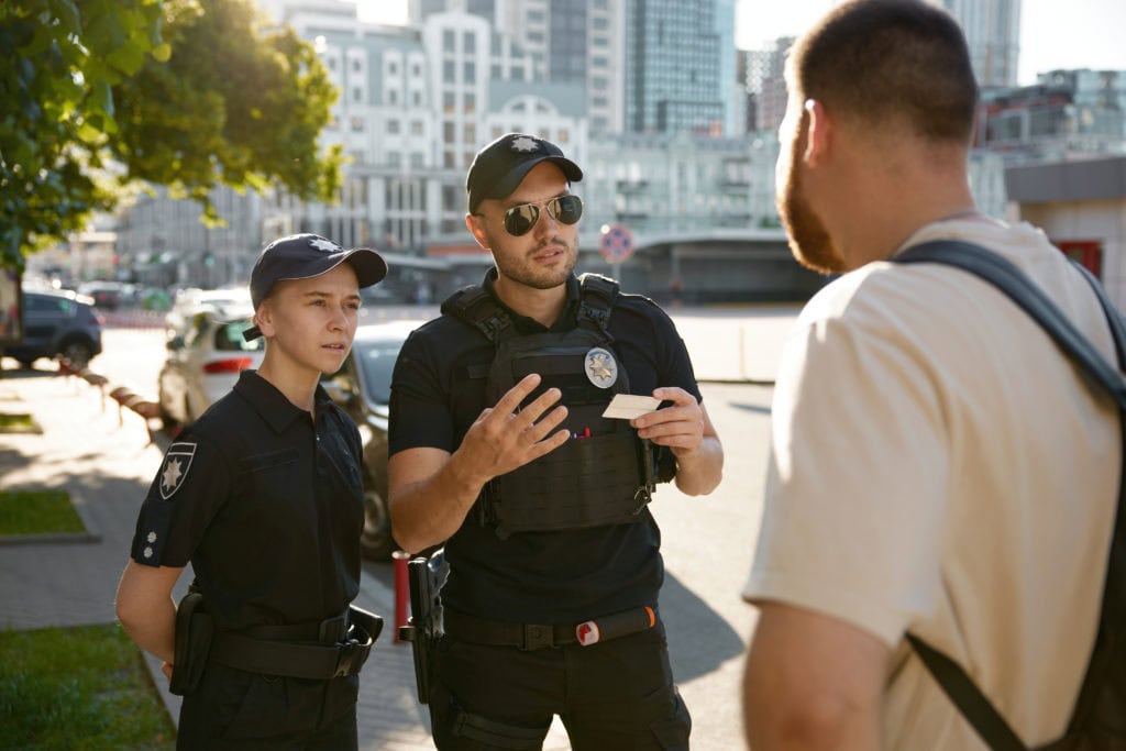 Patrol policeman and policewoman checking personal documents of citizen
