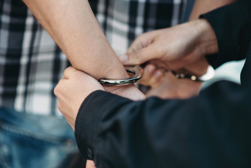 Canadian prison rights and inmate protections shown by police handcuffing a detainee, symbolizing lawful custody and Charter safeguards.