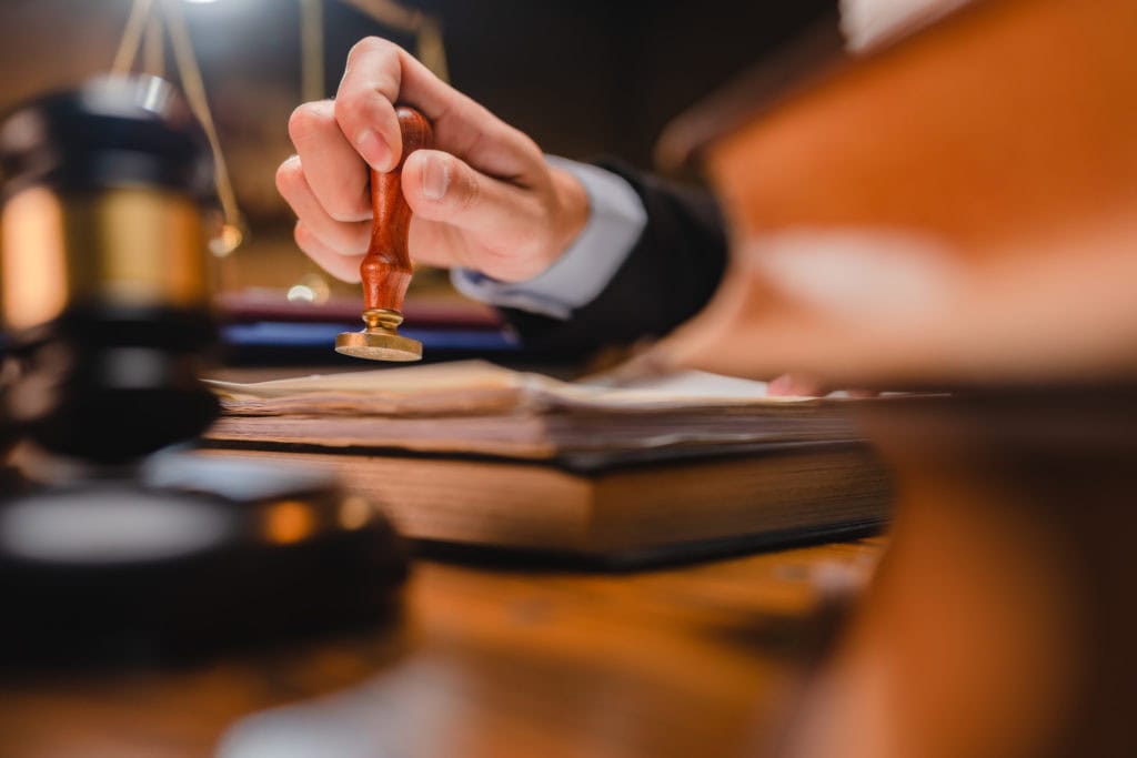 businessman or lawyer put a success stamp on legal deal contract in office, approved on certificate