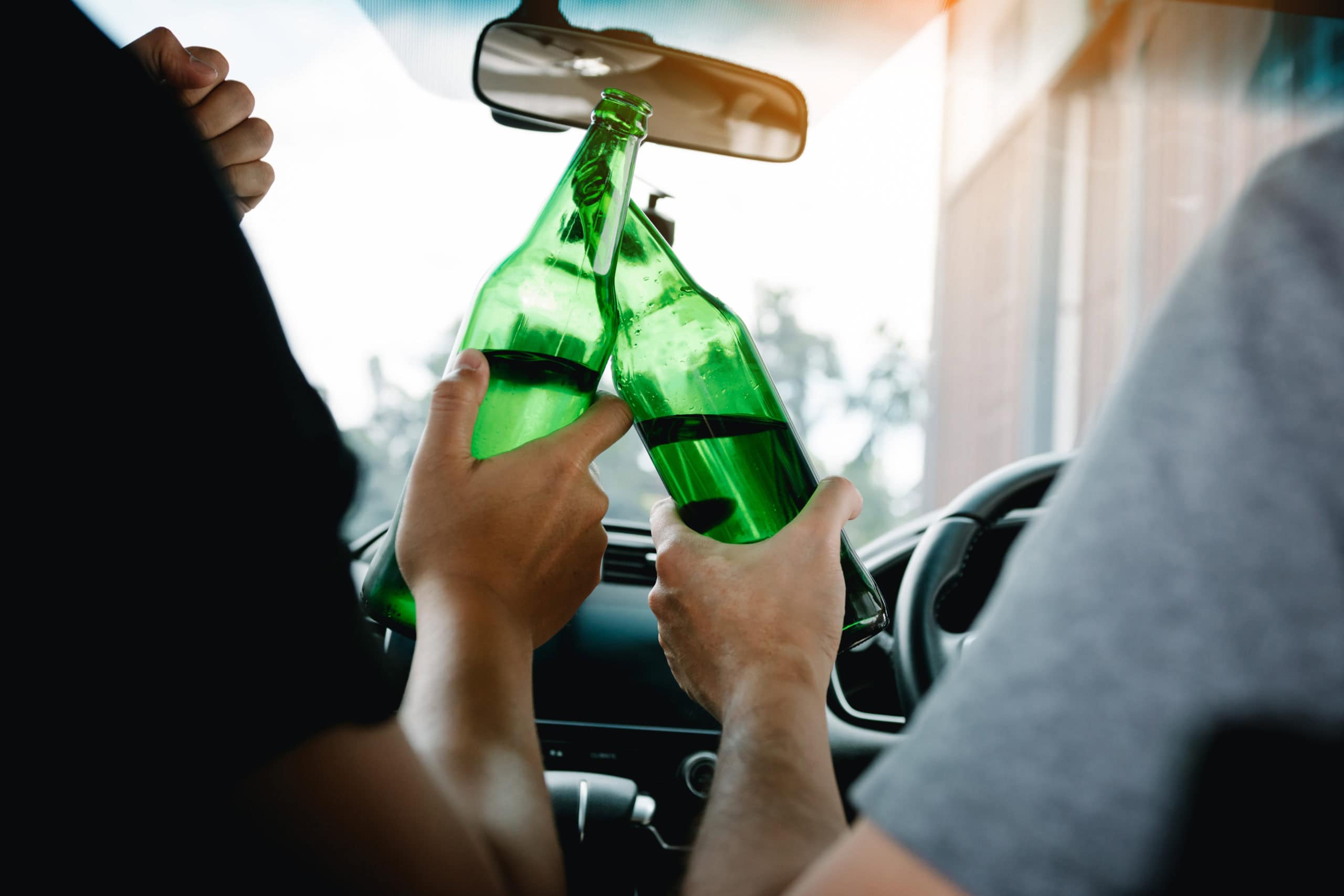 Two male friends are celebrating in the car while they are clink