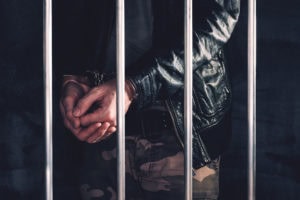 Handcuffed man behind prison bars