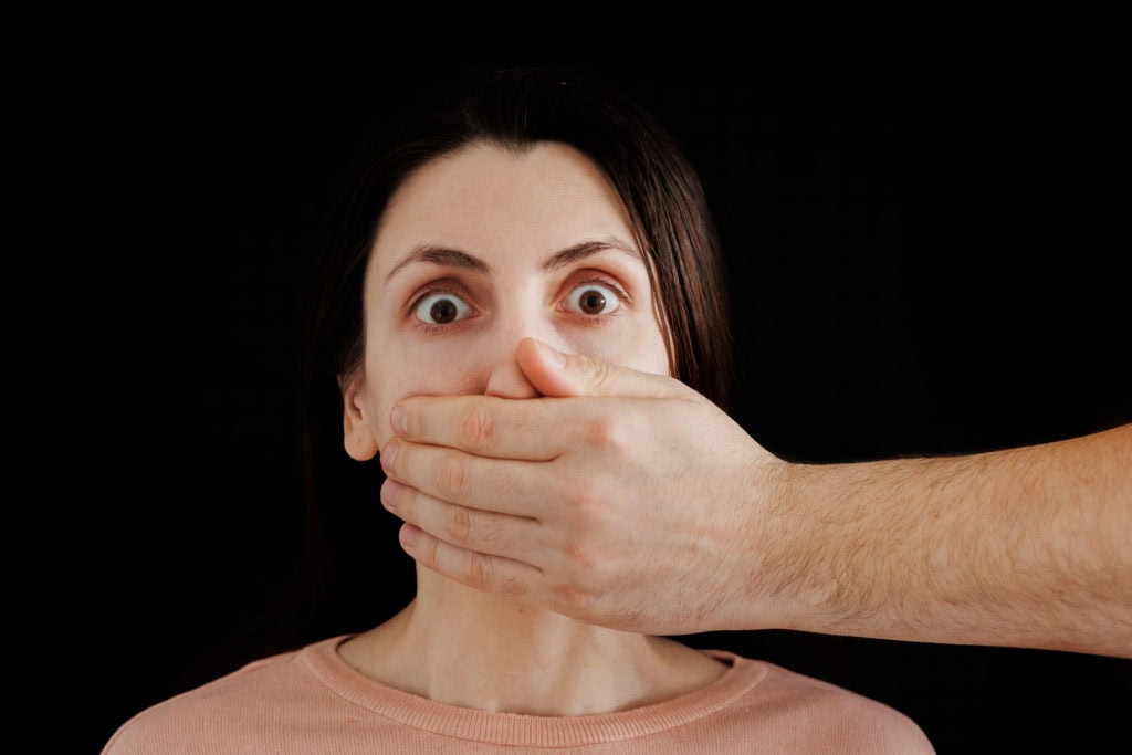 Man hand closes woman mouth, infringement on female rights
