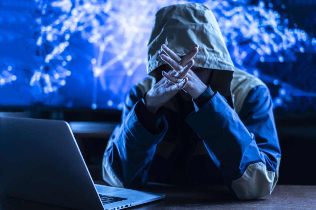 the anonymous hacker braking the personal online data in his office, dark blue, deep web