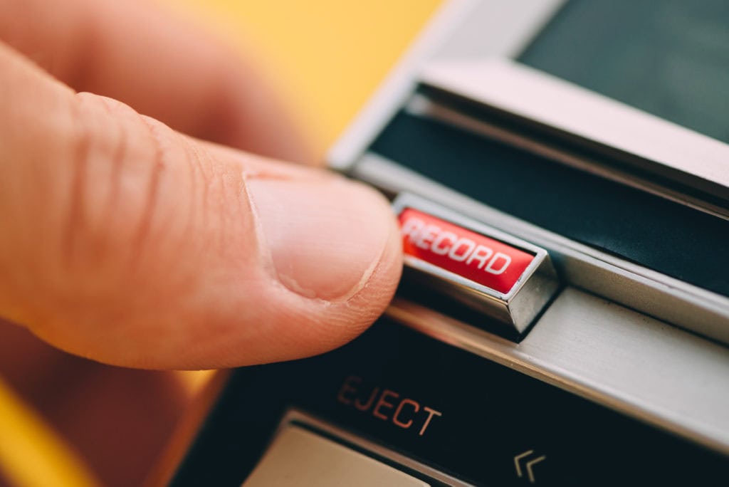 Finger pushing Record button on vintage audio cassette player