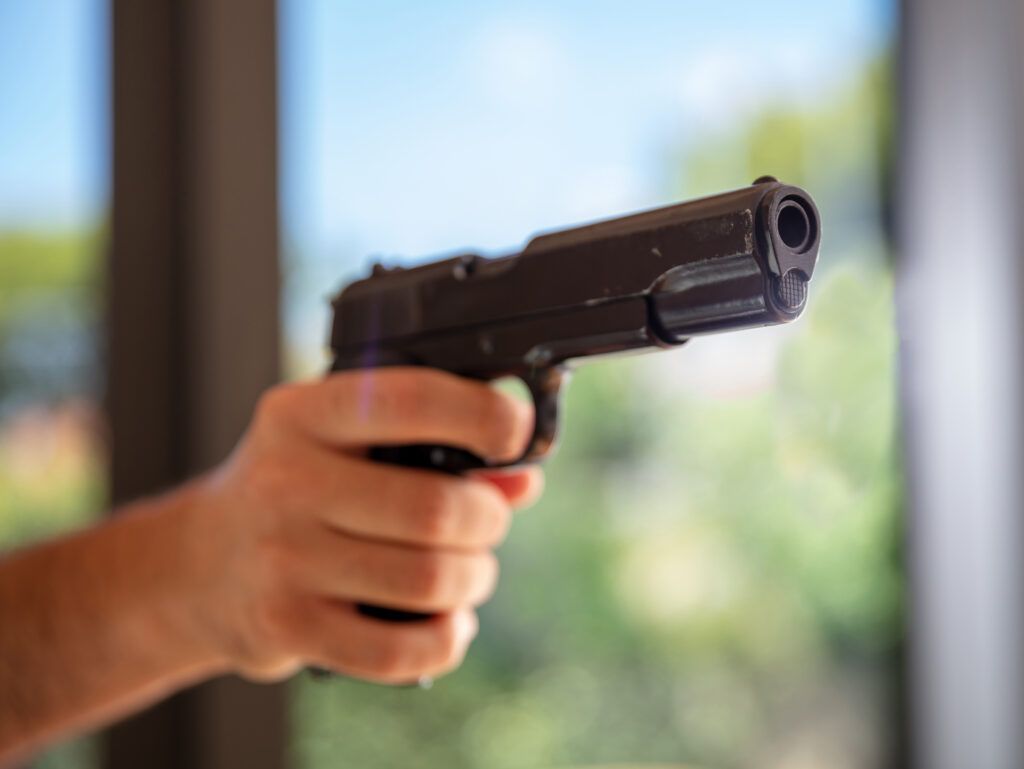 Close-up of a person holding a handgun, representing firearm possession and gun control laws in Canada