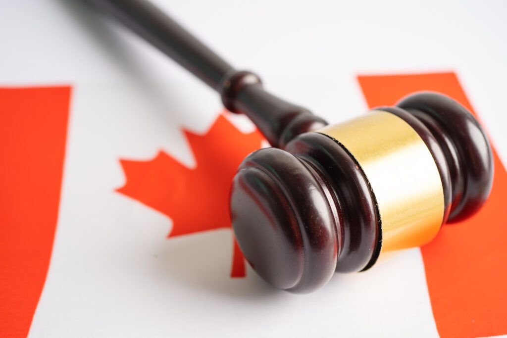 Gavel on Canadian flag symbolizing uttering threats charges under Canada’s Criminal Code and criminal defence rights.